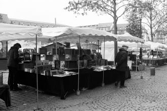 Livros expostos em bancas sob tendas durante um mercado ao ar livre.