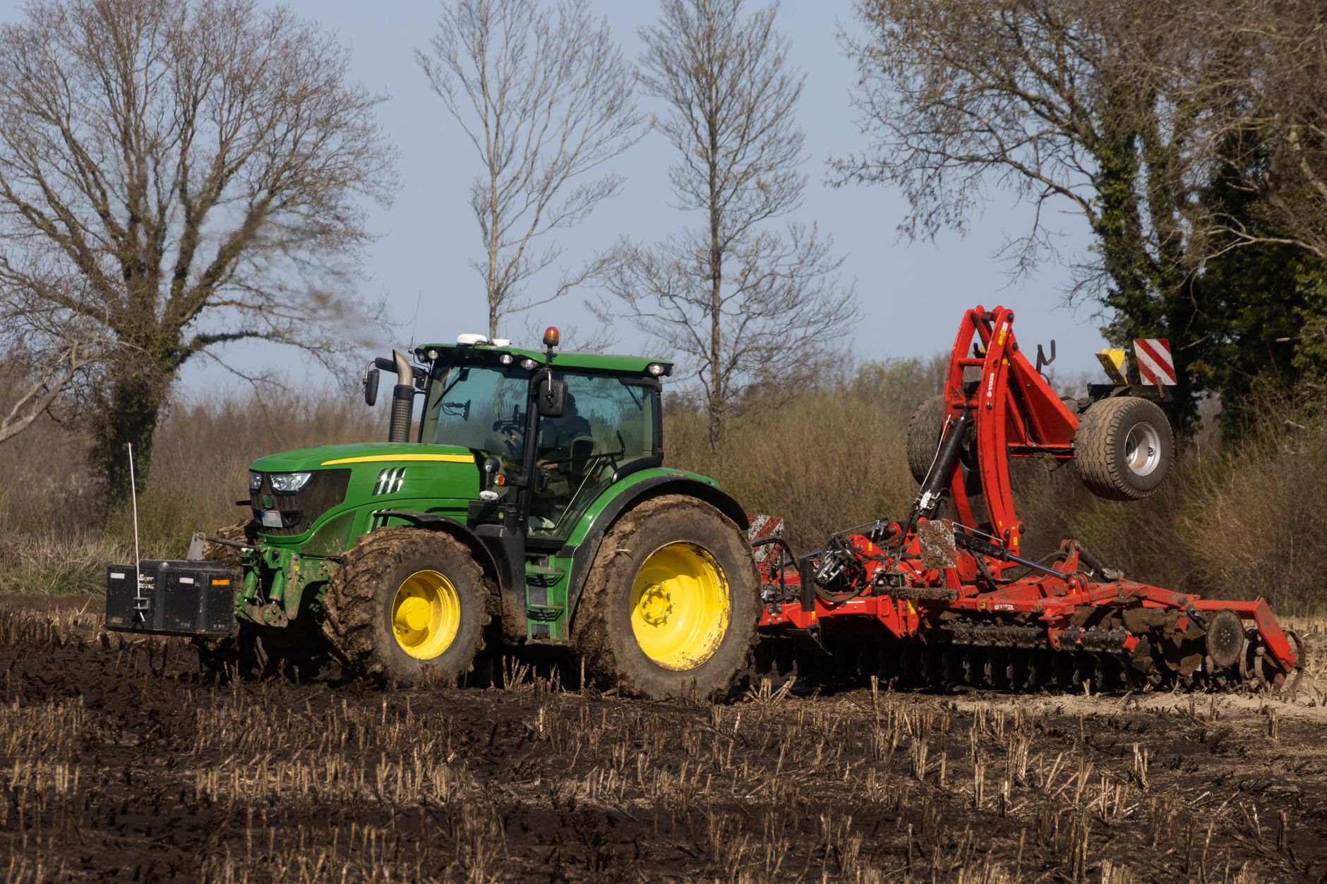 Trator preparando o solo em uma área rural para o plantio.