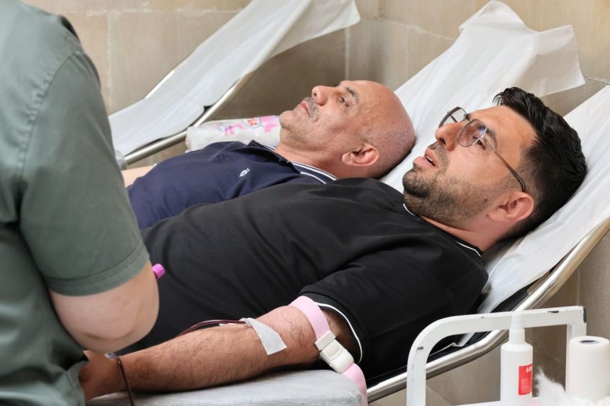 Dois homens deitados em macas enquanto doam sangue em uma clínica