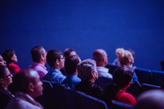 Grupo de adultos acompanha atentamente uma apresentação durante uma conferência em ambiente interno.