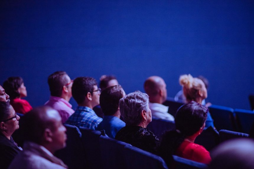 Grupo de adultos acompanha atentamente uma apresentação durante uma conferência em ambiente interno.